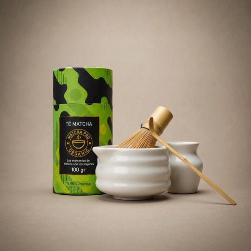 Bote de Té Matcha Premium con estampado verde y negro junto a un chawan de cerámica y un chasen de bambú — MatchaPro