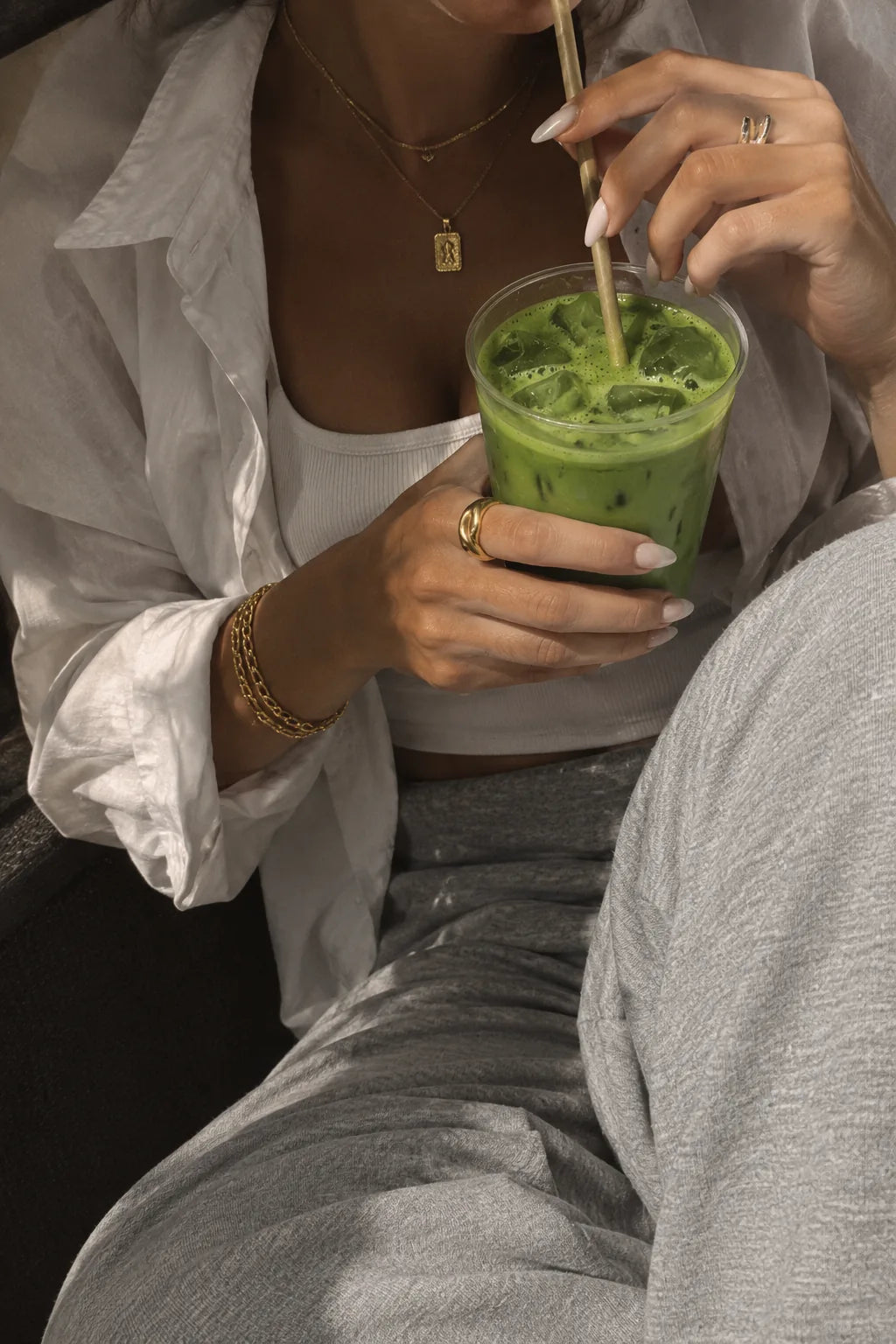 Mano sosteniendo un vaso de matcha latte helado con una pajita